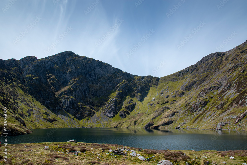 a view looing down in the crater of Cadair Idris with a mountain view behind it	