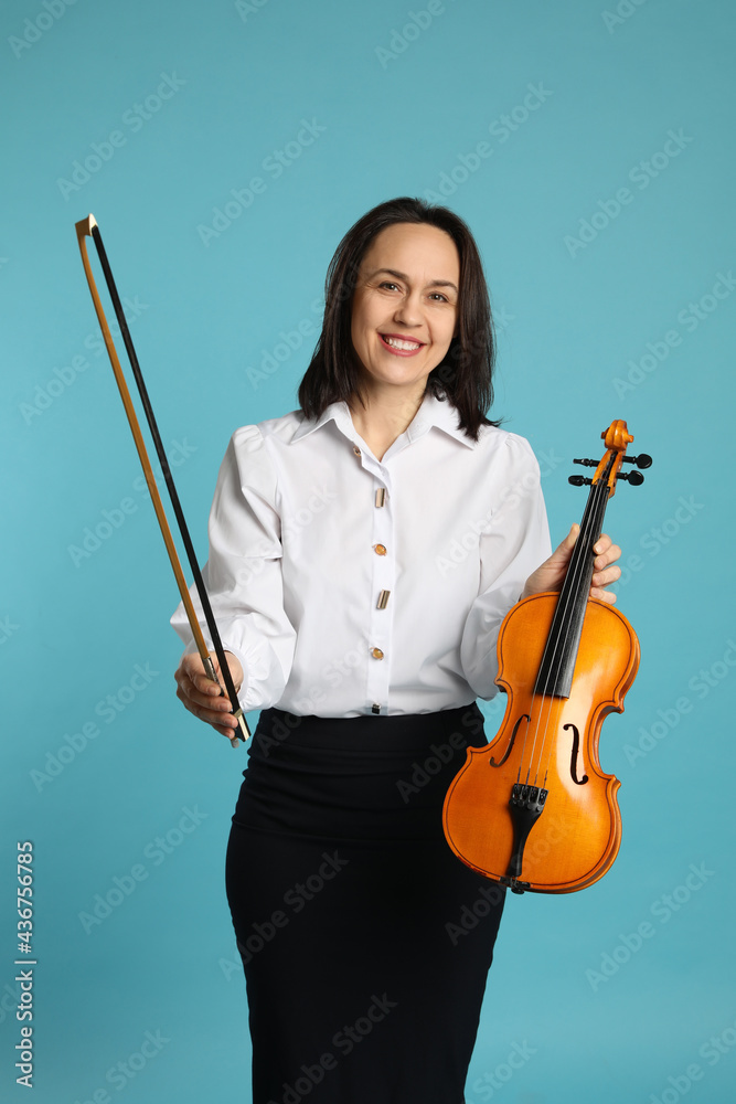 Music teacher with violin and bow on turquoise background Music teacher with violin and bow on turquoise background