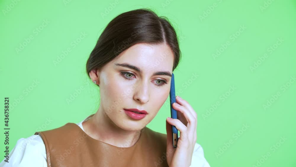 Portrait of young woman with beautiful green eyes is talking on the phone. Businesslady is talking on the smartphone. Green chroma key screen is on the background Portrait of young woman with beautiful green eyes is talking on the phone. Businesslady is talking on the smartphone. Green chroma key screen is on the background