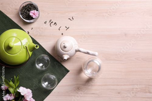 Beautiful traditional tea ceremony set and sakura flowers on wooden table, flat lay. Space for text
