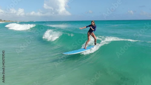 Young woman is surfing on the light blue waves of the ocean, sports