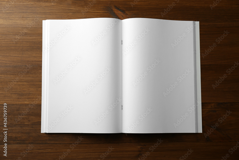 Fototapeta premium Open blank paper brochure on wooden table, top view. Mockup for design
