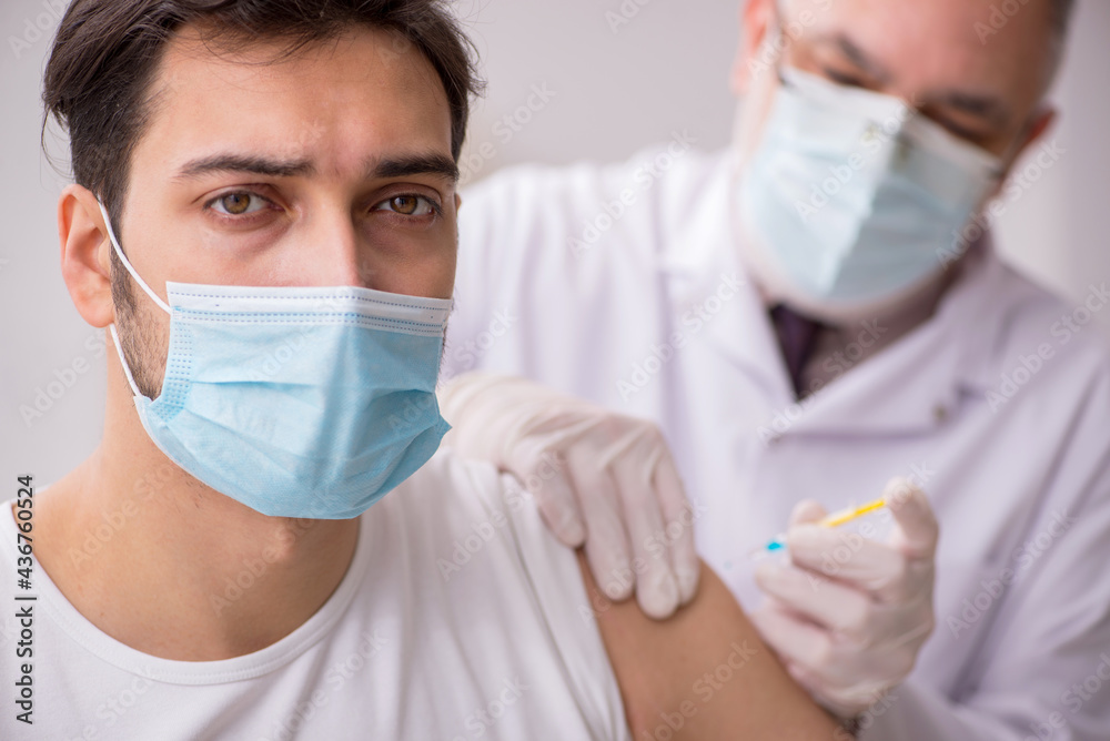 Young male patient visiting old male doctor in vaccination conce