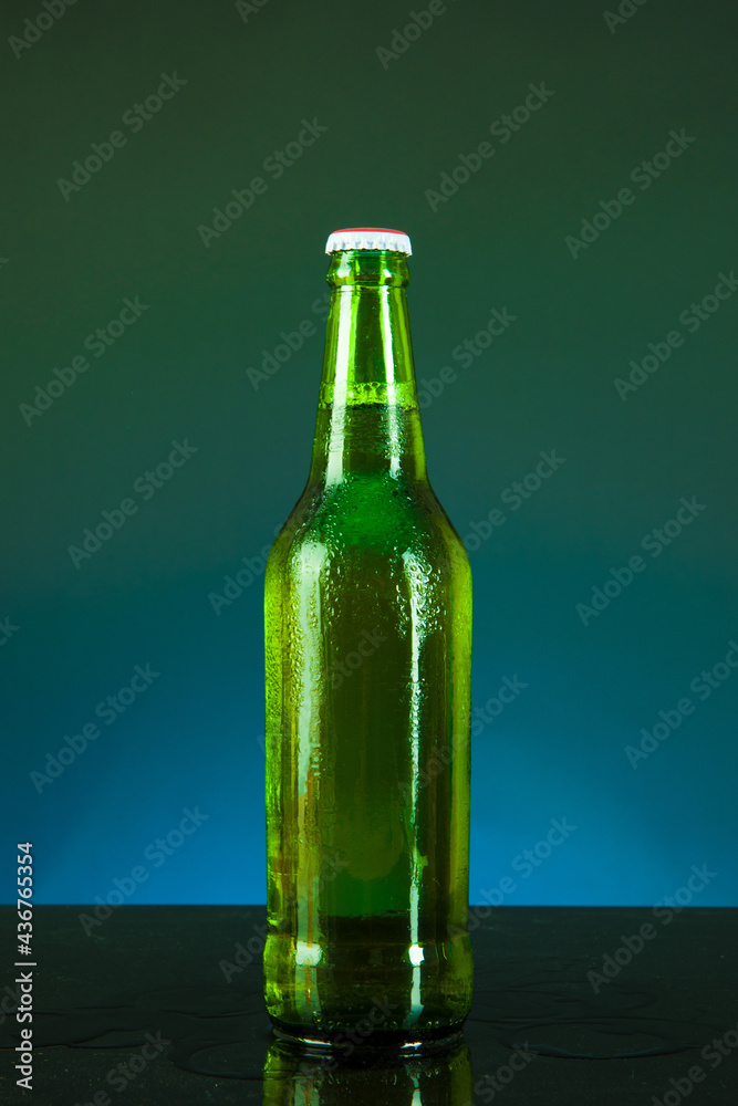 green beer bottle with drops on blue background green beer bottle with drops on blue background