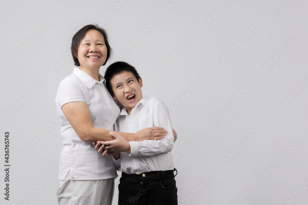 Portrait of Grandmother and grandchild hugging, looking at camera and smiling, on gray background Portrait of Grandmother and grandchild hugging, looking at camera and smiling, on gray background