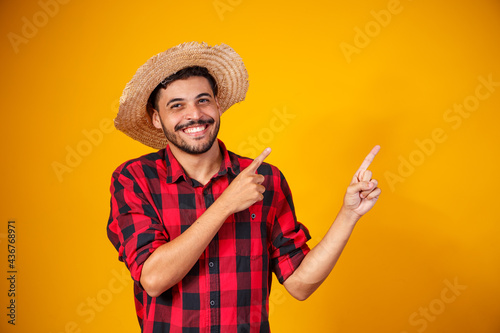 Brazilian man wearing typical clothes for the Festa Junina, Pointing to upper right corner