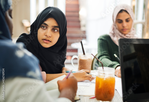 Group of Muslim school girls studying at a cafe together