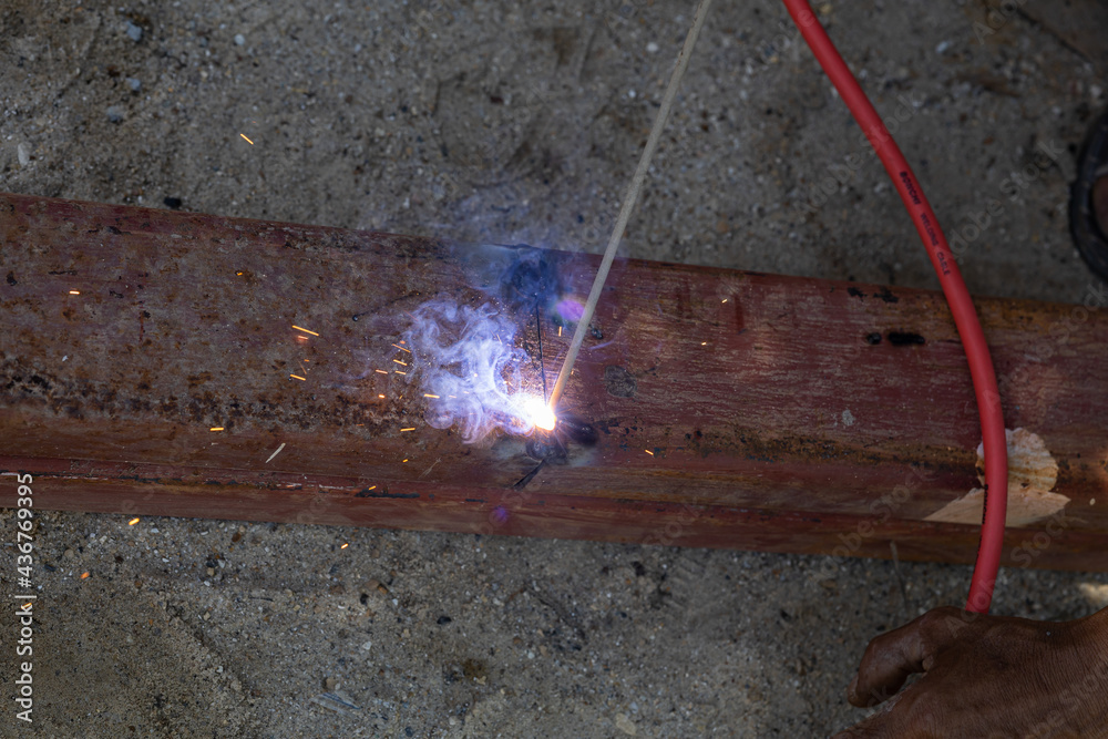 Unsafe worker welding steel beam without hand protection, In concept