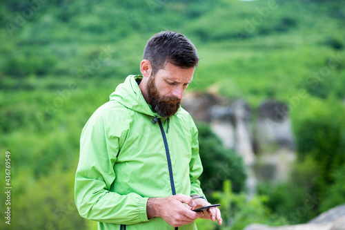 man trekking checking map on smartphone in summer scenery