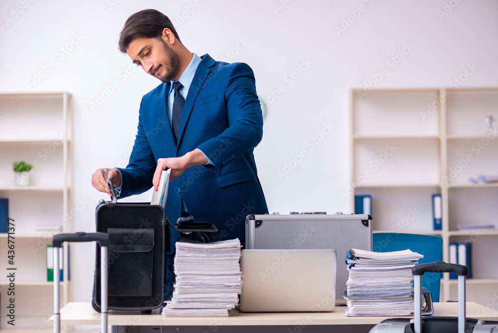 Young male employee preparing for business trip at workplace