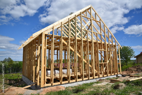 Wood frame residential building under construction.Building construction, wood framing structure at new property development site.new home currently under construction against blue sky.mortgage, loan. © Nina