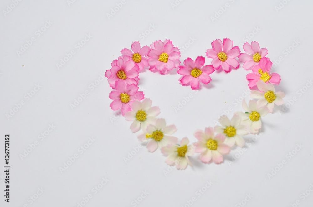 Sweet colored flowers arranged in heart shape on white background copy space.