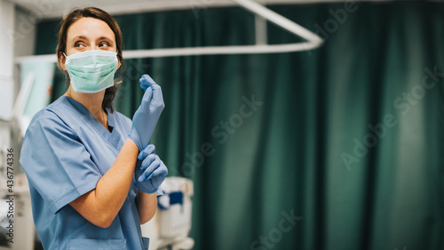 Photo Female nurse with a mask putting on gloves preparing to cure coronavirus patient