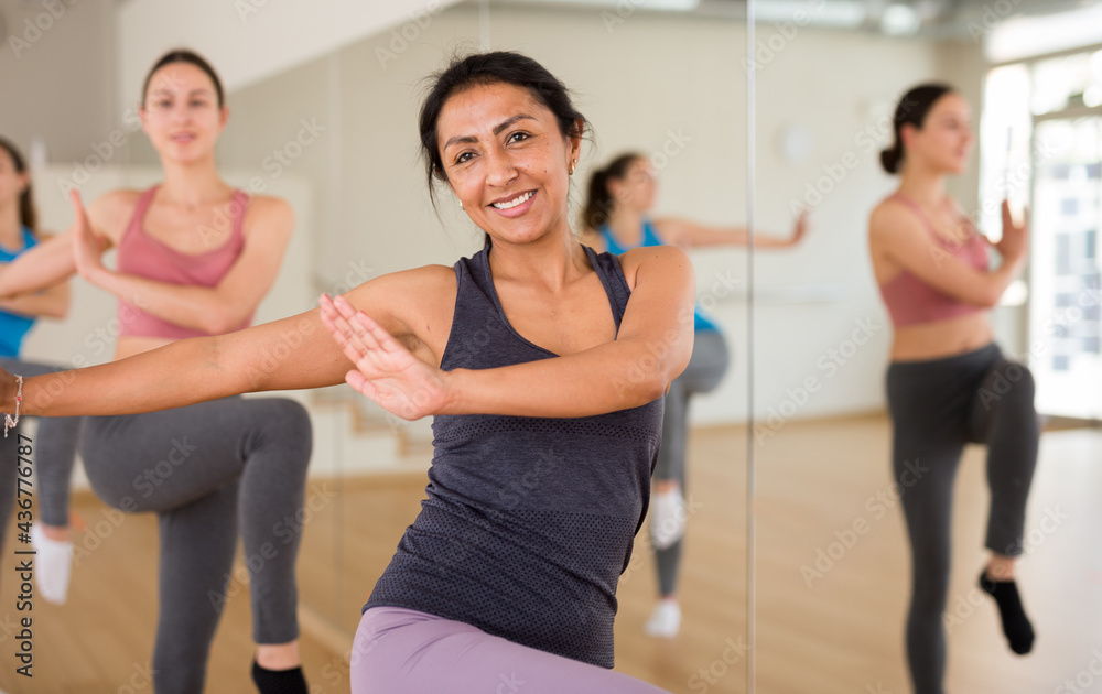 Fototapeta premium Portrait of dancing latin american woman practicing vigorous swing during group training in dance studio.