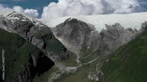 A magnificent Austerdalsbreen crowning the mountains, towering above the lush Langedalen valley, Norway. The glacier is fed by the three steep glaciers Odinbreen, Torbreen, and Lokebreen. Aerial view photo