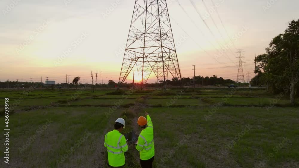 4k VDO, Team work of Engineers and Technician working inspections at the electric power station to view the planning work by producing electricity high voltage electric transmission tower at sunset