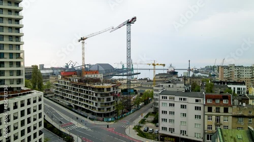 Drone pull back and landing over street scross of Gdynia city, apartment building construction site with many cranes. photo