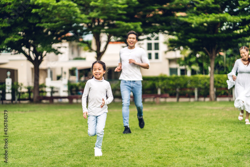 Portrait of enjoy happy love asian family father and mother with little asian girl smiling running playing and having fun moments good time in summer park at home