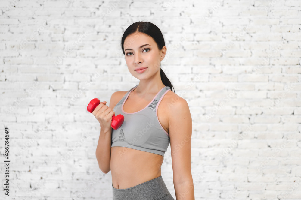 Smiling sporty woman standing taking a break after workout and holding dumbbell at the gym.fitness and lifestyle concept Smiling sporty woman standing taking a break after workout and holding dumbbell at the gym.fitness and lifestyle concept
