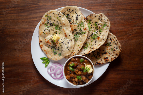 Принти на полотні Close-up of fresh, hot tandoori roti or butter naan garnished with black till and green fresh coriander leaves and chole