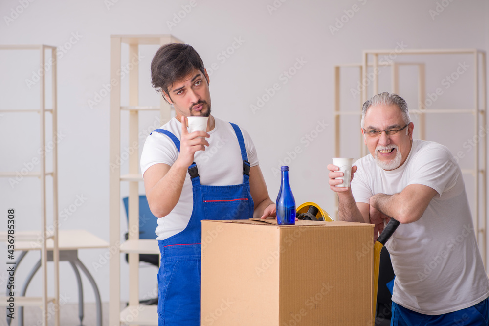 Two male professional movers drinking alcohol during break Two male professional movers drinking alcohol during break