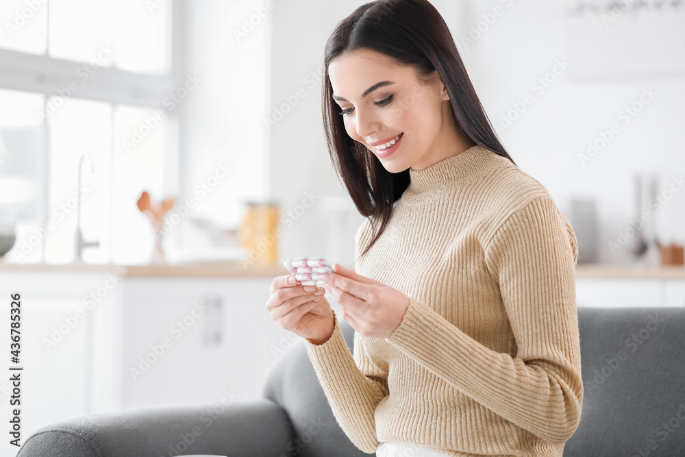 Beautiful young woman taking pills in kitchen Beautiful young woman taking pills in kitchen