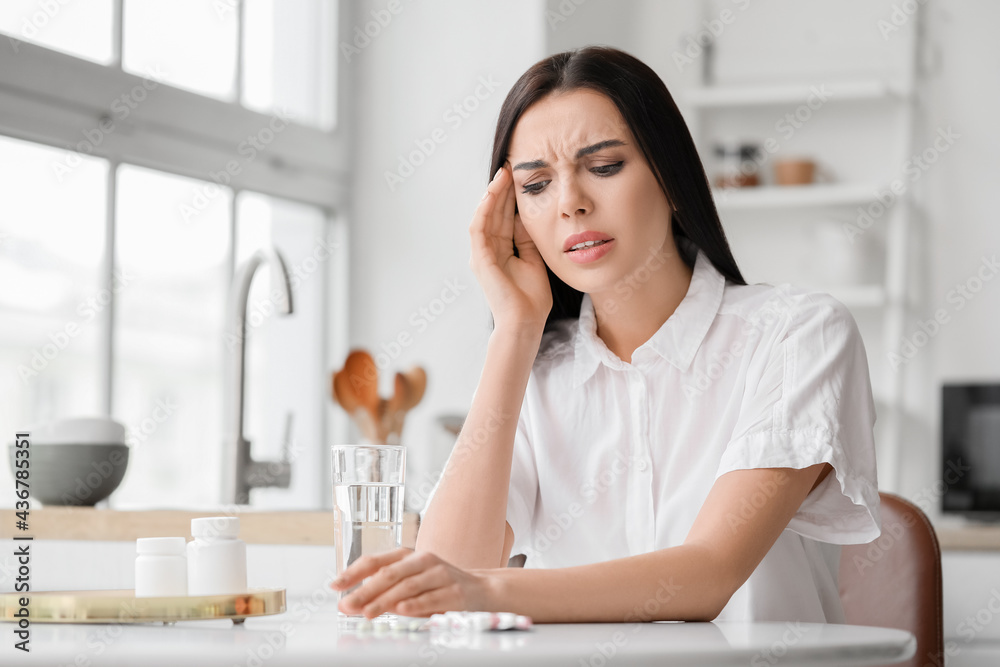 Beautiful young woman with pills suffering from headache at home Beautiful young woman with pills suffering from headache at home