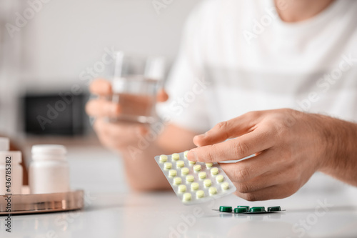 Handsome young man taking pills at home
