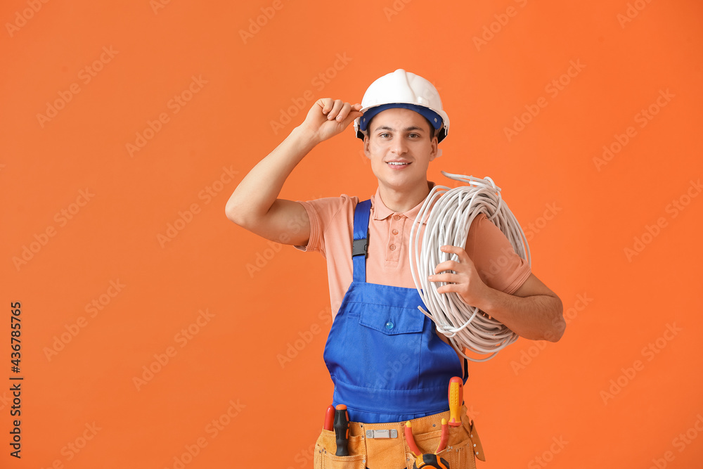 Young electrician with cables on color background Young electrician with cables on color background