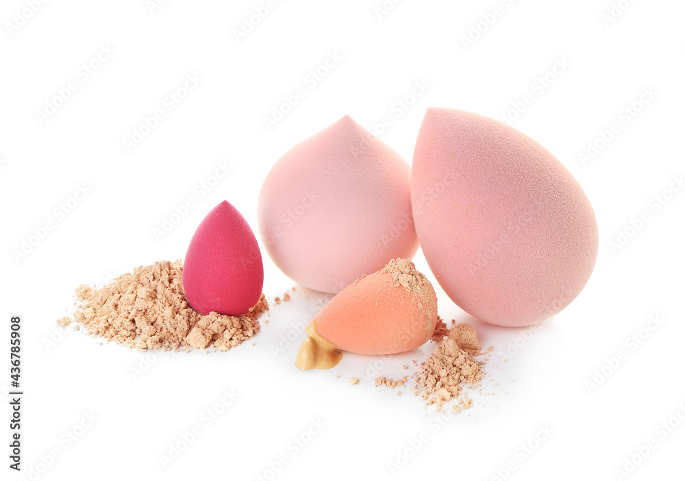 Makeup sponges, liquid foundation and powder on white background