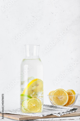 Bottle of tasty cold lemonade on light background