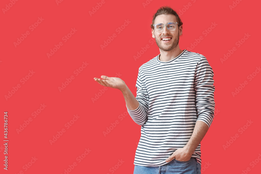 Young man wearing eyeglasses and showing something on color background Young man wearing eyeglasses and showing something on color background