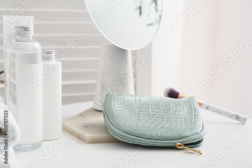 Stylish bag with decorative cosmetics on table in room