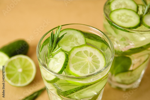 Glasses with cucumber lemonade on color background