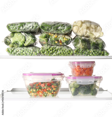 Plastic containers and bags with frozen vegetables on white background