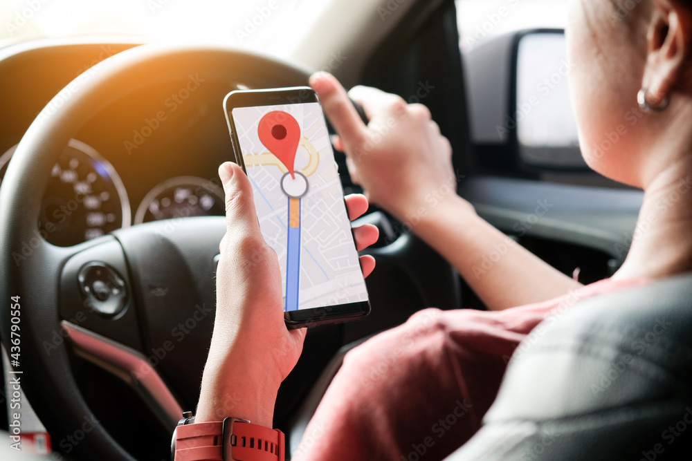 A woman car driving on the road And she is looking for a GPS map on a smartphone to get to the destination of the route. Concept of technology and road traffic A woman car driving on the road And she is looking for a GPS map on a smartphone to get to the destination of the route. Concept of technology and road traffic