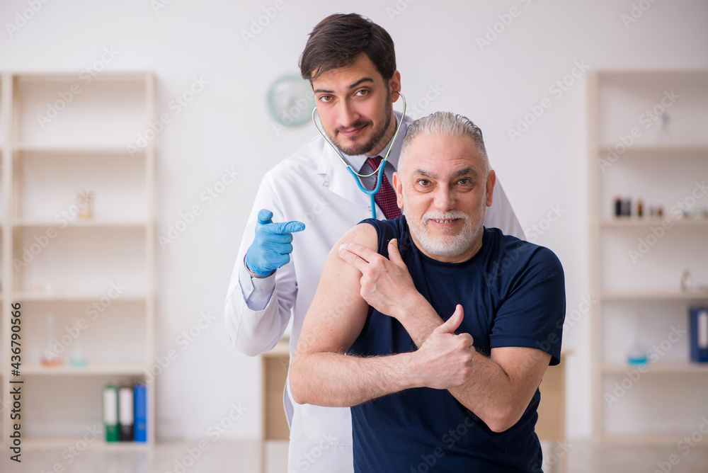 Old male patient visiting young male doctor in vaccination conce Old male patient visiting young male doctor in vaccination conce