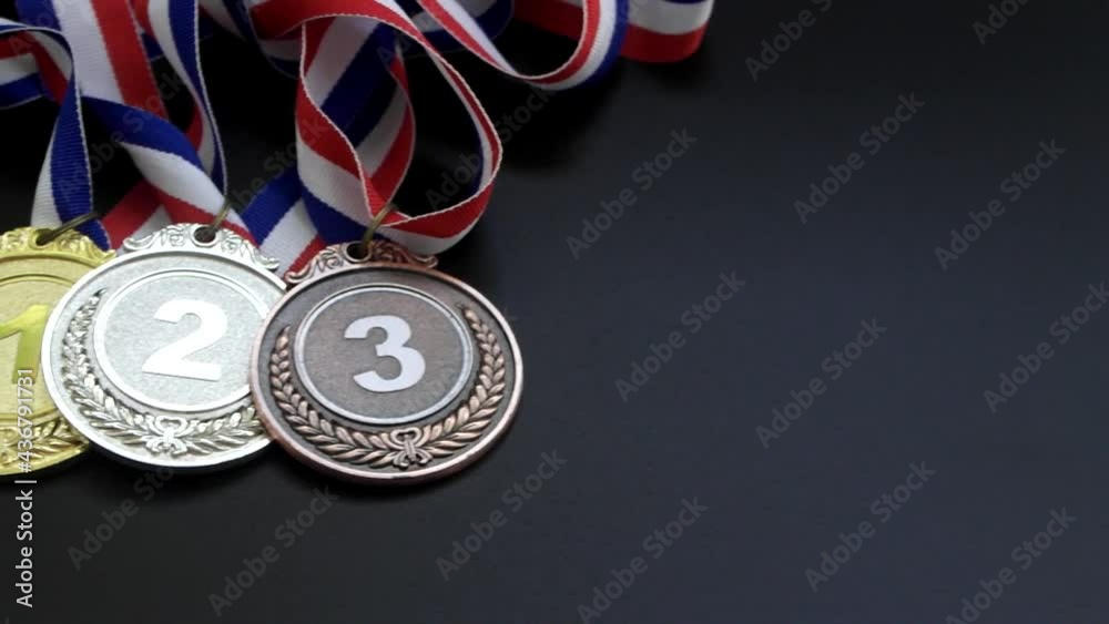 Gold, silver and bronze medal with ribbons on black table Gold, silver and bronze medal with ribbons on black table