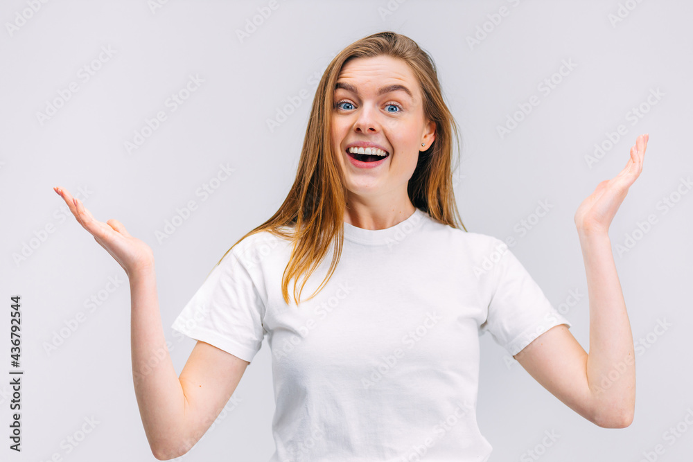 Fototapeta premium Surprised happy beautiful woman looking at the camera in excitement. The girl holds her hands to the side in surprise