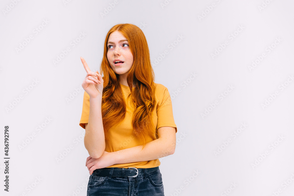 pensive girl points up with a forefinger at a blank spatial, shows a place for your advertisement or ad text pensive girl points up with a forefinger at a blank spatial, shows a place for your advertisement or ad text