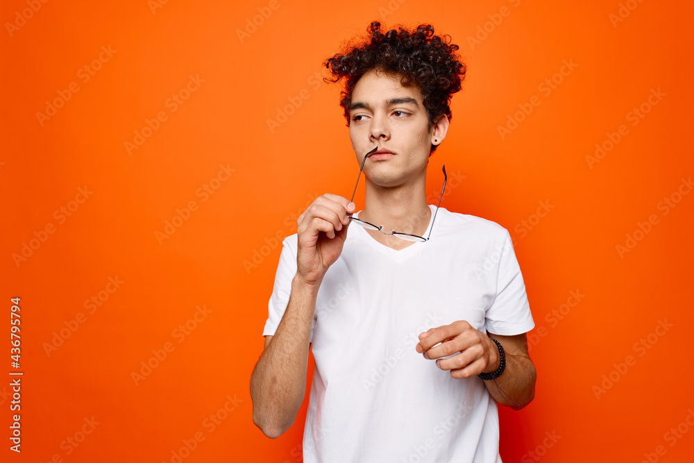 man with curly hair and glasses white t-shirt licks orange background man with curly hair and glasses white t-shirt licks orange background