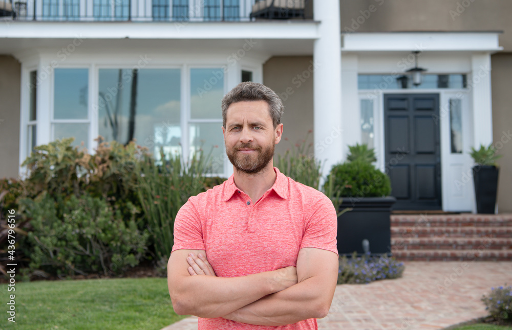 Portrait of a happy man standing outside house.