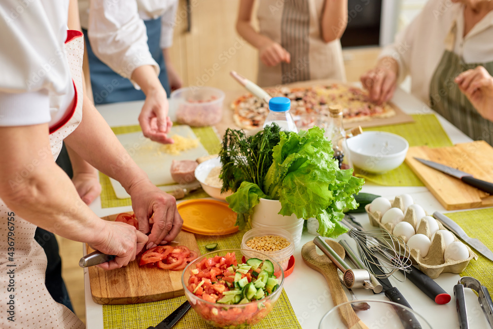 Close-up photo of table with female hands cutting ingredients for dinner, preparing meal, using cutting board. Food, dinner, meal, cook concept