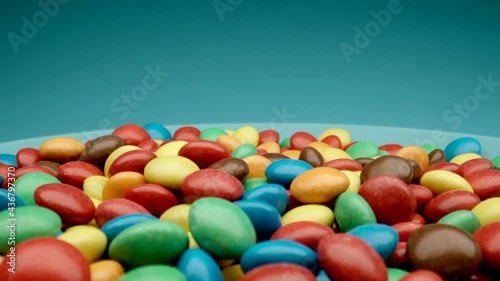 MACRO: Many colored canies on a blue dish, Dolly motion