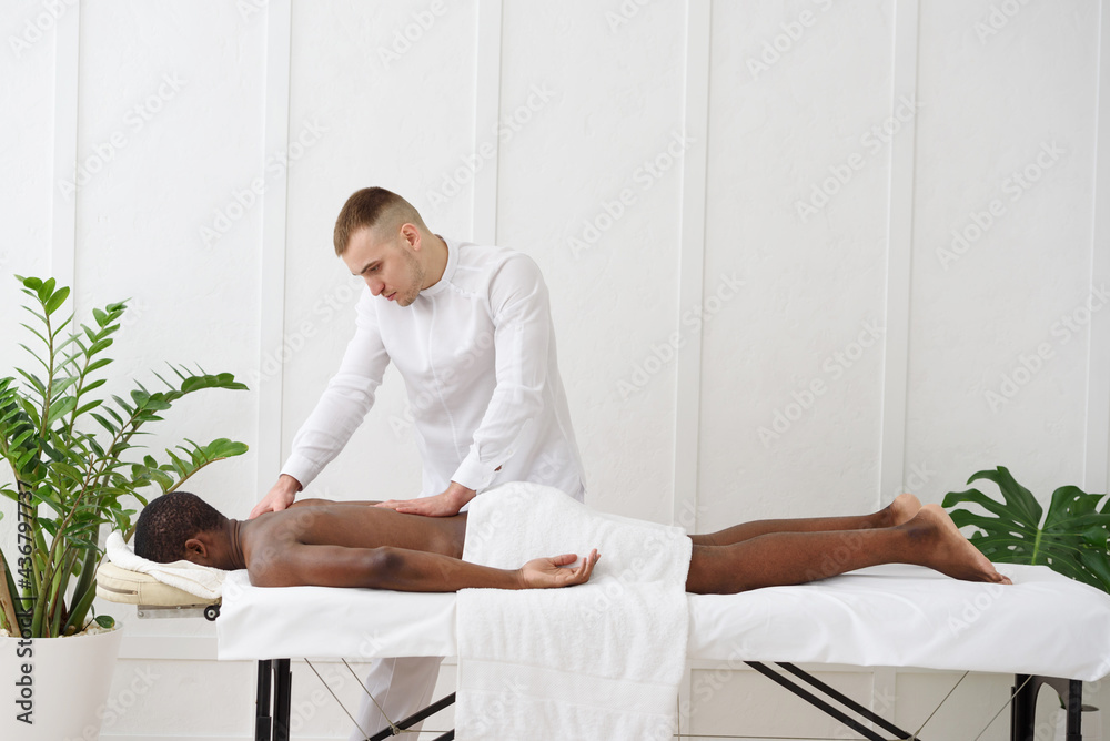African american man having back massage in spa, white background. Copy space African american man having back massage in spa, white background. Copy space