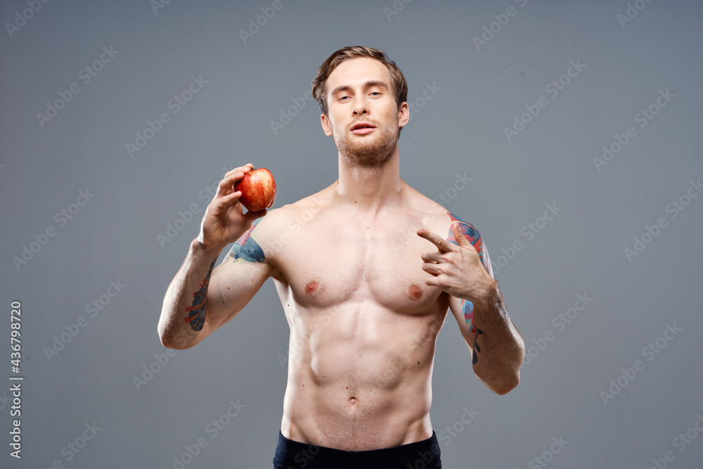 athletic guy with a pumped up torso healthy lifestyle nutrition vitamins red apple