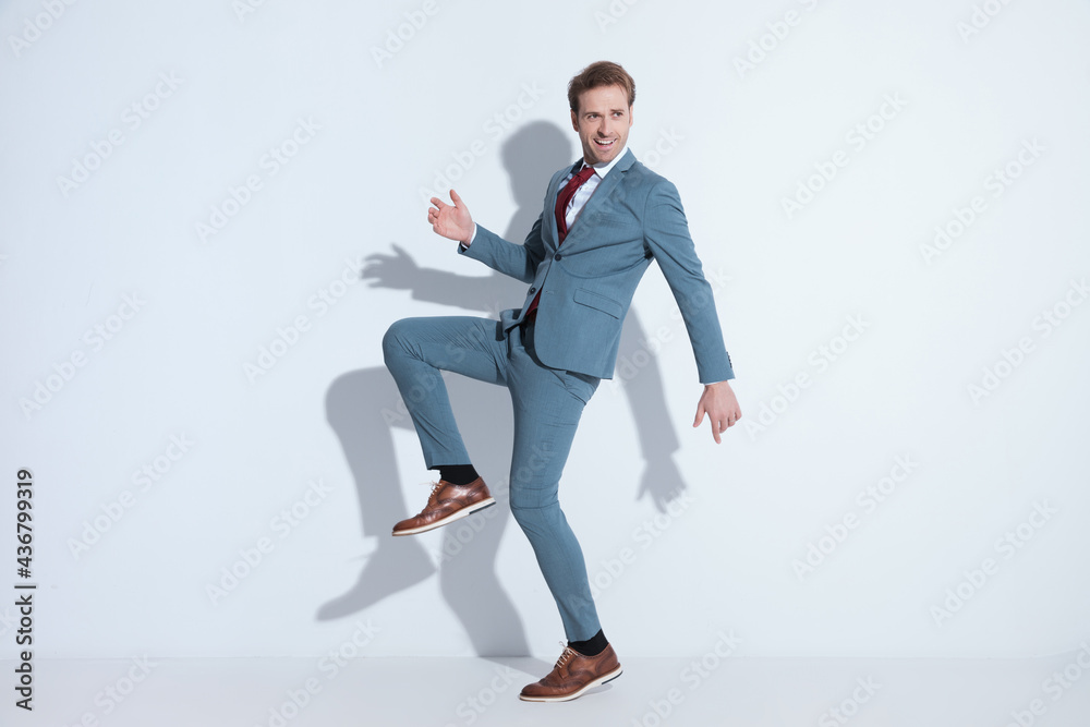 side view of happy businessman holding knee up and posing