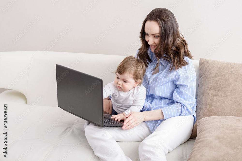 woman with baby watching cartoons on laptop sitting on couch, remote work at home with children, young mother on maternity leave woman with baby watching cartoons on laptop sitting on couch, remote work at home with children, young mother on maternity leave
