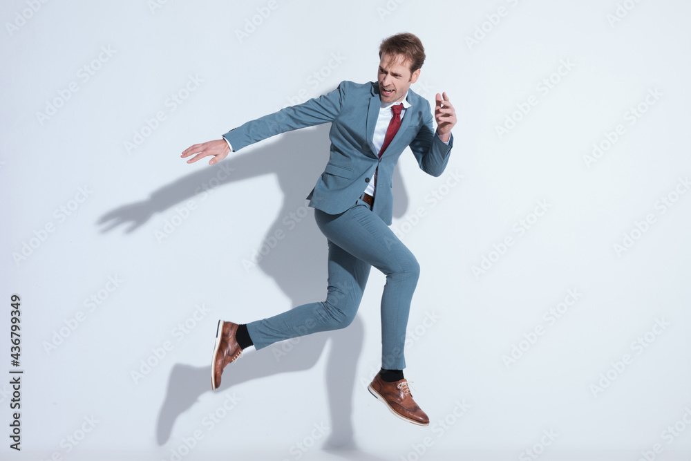 side view of dynamic young elegant guy looking to side and jumping side view of dynamic young elegant guy looking to side and jumping