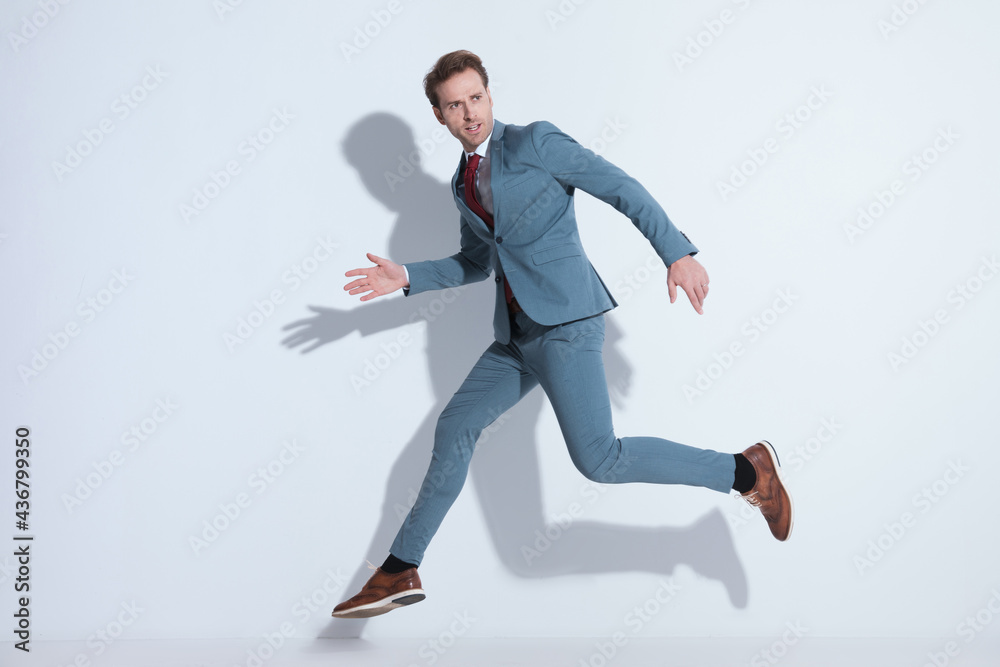 cool elegant man in blue suit looking to side and jumpingi in the air